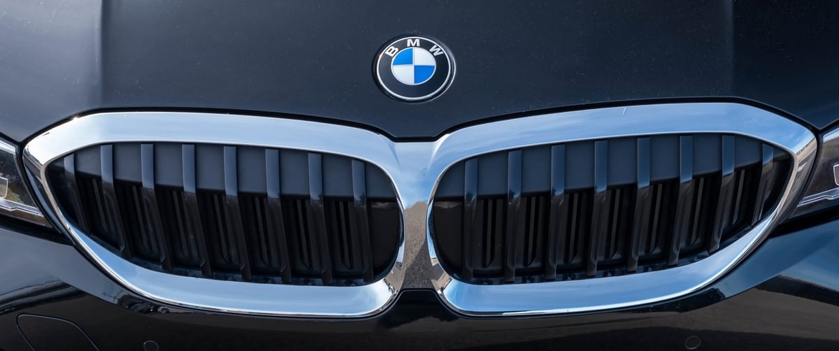 Glossy black BMW paint with kidney grilles and roundel in bright sunlight